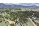 An aerial view of the property nestled among mature trees with other houses in the distance at 3640 Summertime Ct, Monument, CO 80132