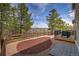 Landscaped backyard featuring wood fencing, mulch ground cover, green trees, and a deck with hot tub and barbecue at 3640 Summertime Ct, Monument, CO 80132