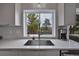 Kitchen featuring white herringbone backsplash, stainless steel sink and a view of the outdoors at 3640 Summertime Ct, Monument, CO 80132