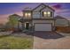 Charming two-story home with a well-manicured lawn and a brick driveway in the evening at 18366 E 102Nd Pl, Commerce City, CO 80022