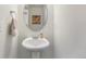 Simple half-bathroom featuring a white pedestal sink, round mirror and wall decor at 18366 E 102Nd Pl, Commerce City, CO 80022