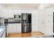 Kitchen area featuring stainless steel refrigerator and white cabinetry with wood flooring at 14032 E Chenango Dr, Aurora, CO 80015