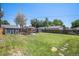 Spacious backyard with a well-maintained lawn, wooden fence, and multiple outbuildings at 2465 W Mosier Pl, Denver, CO 80223