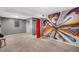 Finished basement with vibrant wall art, a red door, a window, and closet space, offering a colorful living area at 2465 W Mosier Pl, Denver, CO 80223