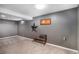 Carpeted basement with a small window, a minimalist bench, and unique wall art, providing a functional space at 2465 W Mosier Pl, Denver, CO 80223