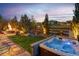 Serene backyard with a relaxing hot tub, a cozy fire pit, lush landscaping, and views of neighboring properties at 14582 Mission Walk Loop, Parker, CO 80134