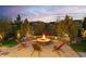 Outdoor fire pit area with comfortable seating and mature trees in a serene backyard setting under a colorful sky at 14582 Mission Walk Loop, Parker, CO 80134