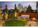 Tranquil backyard with an illuminated hot tub, green lawn, mature trees, and a wooden fence for privacy at 14582 Mission Walk Loop, Parker, CO 80134