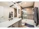 Modern bathroom featuring gray subway tile, glass shower door, and vanity with Carrara marble countertop and black fixtures at 10694 Cedarcrest Cir, Highlands Ranch, CO 80130