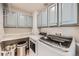 This modern laundry room features blue-grey cabinets, granite countertop, and a high-end washer and dryer set at 10694 Cedarcrest Cir, Highlands Ranch, CO 80130