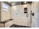 Luxurious walk-in shower with gray tile, rain shower head, bench, and black slate tile flooring at 10694 Cedarcrest Cir, Highlands Ranch, CO 80130