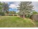 Spacious backyard with lush green lawn and mature trees bordered by a wooden fence at 7112 S Platte Canyon Dr, Littleton, CO 80128