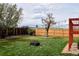 A lush backyard with vibrant green grass, privacy fence, a black fire pit, and string lights for evening enjoyment at 4303 S Yank St, Morrison, CO 80465