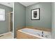 Elegant bathroom featuring a soaking tub with tile surround and glass-enclosed shower at 5193 Rustic Ave, Firestone, CO 80504
