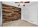 Comfortable bedroom featuring wood accent wall, ceiling fan, and spacious closet space at 5193 Rustic Ave, Firestone, CO 80504