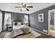 Gray bedroom with ceiling fan, carpet, and large bed with view of bathroom entrance at 5193 Rustic Ave, Firestone, CO 80504