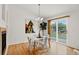 Bright dining area featuring a modern chandelier, white table and hardwood floors with backyard views at 5193 Rustic Ave, Firestone, CO 80504
