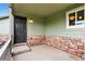 Welcoming front porch area with a decorative brick facade and a traditional black door at 5193 Rustic Ave, Firestone, CO 80504