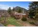 Secluded backyard showcasing mature trees, lush lawn, and a cozy brick home at 25 High St, Palmer Lake, CO 80133