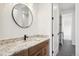Bathroom with wood cabinets, granite countertop, modern fixtures and a round mirror above the sink at 555 Coal Bank Trl, Castle Rock, CO 80104