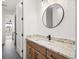Bathroom with wood cabinets, granite countertop, modern fixtures and a round mirror above the sink at 555 Coal Bank Trl, Castle Rock, CO 80104