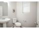 Neutral powder room featuring a pedestal sink, toilet, and window at 17600 Rose Heath Ln, Parker, CO 80134