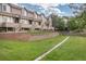 Beautiful townhouse complex with a serene backyard featuring a green lawn, retaining wall, and mature trees at 5555 E Briarwood Ave # 1404, Centennial, CO 80122