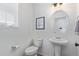 Well-lit half bath with a pedestal sink and decorative mirror at 1079 Larkspur Dr, Erie, CO 80516