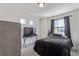 Bedroom with black bedding, tv and stand, and large window with curtains at 1079 Larkspur Dr, Erie, CO 80516