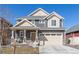 Charming two-story home featuring a covered porch, stone accents, and a two-car garage at 1079 Larkspur Dr, Erie, CO 80516