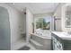Bright bathroom featuring a whirlpool tub beneath a skylight, a separate shower and white tile floors at 15207 W Ellsworth Pl, Golden, CO 80401