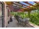 Inviting outdoor patio with brick floor and overhead wood pergola covered with lush greenery at 15207 W Ellsworth Pl, Golden, CO 80401