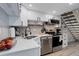 Updated kitchen boasting white cabinets, quartz countertops, stainless appliances, and adjacent carpeted stairs at 1885 S Quebec Way # D22, Denver, CO 80231