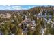 An aerial view of a multi-story home surrounded by mature pines and snowy landscape at 3064 Elk View Dr, Evergreen, CO 80439