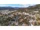Scenic aerial view of residences nestled among the snow-dusted trees with a mountain backdrop at 3064 Elk View Dr, Evergreen, CO 80439