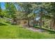 Scenic backyard of a home with lush green grass, mature trees, and a stone exterior at 3064 Elk View Dr, Evergreen, CO 80439