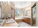 Bright bathroom featuring a soaking tub, double vanity with wood cabinets and a tile floor at 3064 Elk View Dr, Evergreen, CO 80439