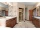 Bathroom with a walk-in shower, double vanity with granite counters and wood cabinets at 3064 Elk View Dr, Evergreen, CO 80439