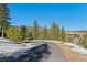 An asphalt driveway leading to residences bordered by mature trees and snow coverage at 3064 Elk View Dr, Evergreen, CO 80439