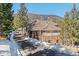 Beautiful home nestled in a wooded landscape, showcasing a stone facade and a spacious three-car garage at 3064 Elk View Dr, Evergreen, CO 80439