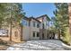 Exterior view of a multi-story home with stone accents, large windows, and a backdrop of tall trees at 3064 Elk View Dr, Evergreen, CO 80439
