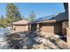 Three-car garage with brown doors, stone accents, a driveway, and solar panels on the roof at 3064 Elk View Dr, Evergreen, CO 80439