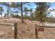 Property boundary entrance featuring fencing and signage surrounded by mature trees and natural landscape at 3064 Elk View Dr, Evergreen, CO 80439