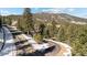 Street view of paved road leading to mountain residences surrounded by mature trees and snow at 3064 Elk View Dr, Evergreen, CO 80439