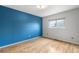 Bedroom with bright blue accent wall, wood floors, and window with shade at 229 Berthoud Way, Golden, CO 80401