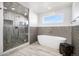 Modern bathroom with a glass-enclosed shower, soaking tub, and stone tile accent wall at 5086 N Raleigh St, Denver, CO 80212