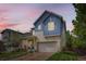 Two-story blue home featuring a two-car garage, covered porch, and manicured lawn at 859 Equinox Dr, Erie, CO 80516