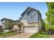Two-story blue home featuring a two-car garage, covered porch, and manicured lawn at 859 Equinox Dr, Erie, CO 80516