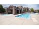 Community pool and hot tub area with stone pillars for building and stone deck at 10056 W Unser Dr # 106, Littleton, CO 80127