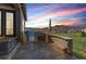 Outdoor kitchen with built-in grill on stone patio overlooking mountain views at sunset at 2363 S Lupine Way, Denver, CO 80228